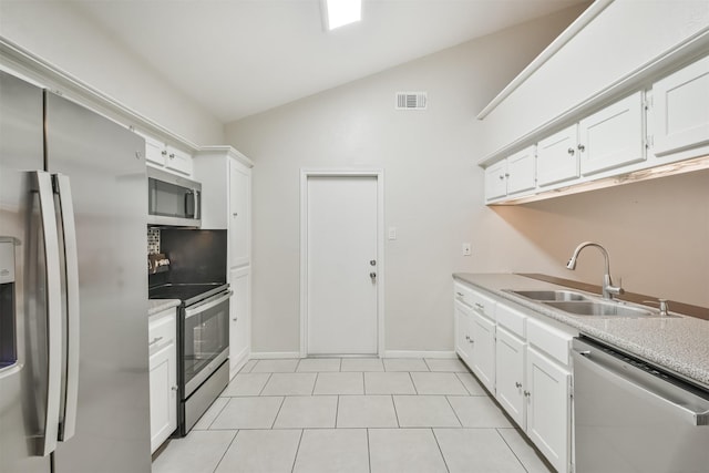 kitchen featuring appliances with stainless steel finishes, white cabinetry, lofted ceiling, and sink