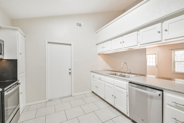 kitchen with dishwasher, sink, vaulted ceiling, light tile patterned flooring, and white cabinetry