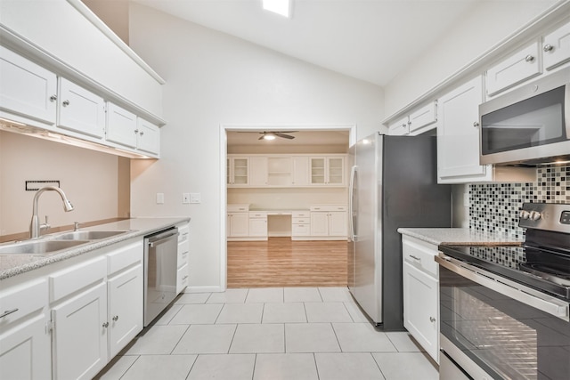 kitchen with decorative backsplash, stainless steel appliances, sink, white cabinetry, and lofted ceiling