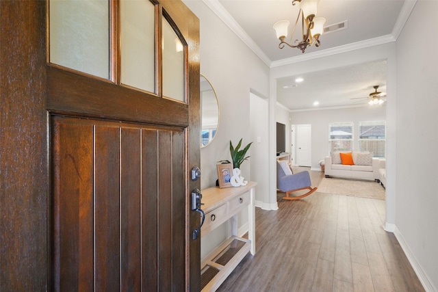 foyer featuring hardwood / wood-style flooring, ceiling fan with notable chandelier, and ornamental molding