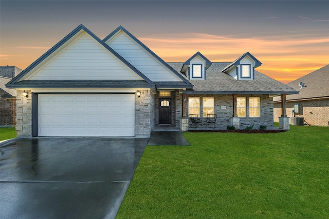 view of front of home featuring a lawn, cooling unit, a porch, and a garage