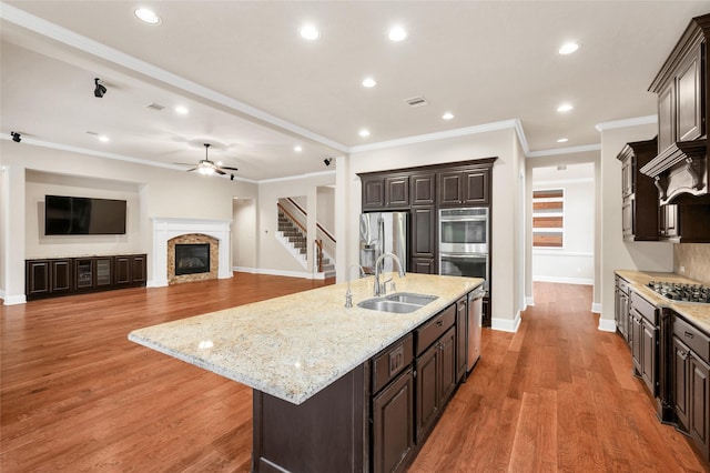 kitchen with a spacious island, sink, ceiling fan, appliances with stainless steel finishes, and dark brown cabinetry