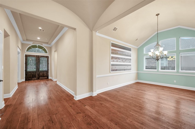 entryway featuring hardwood / wood-style floors, an inviting chandelier, french doors, vaulted ceiling, and ornamental molding