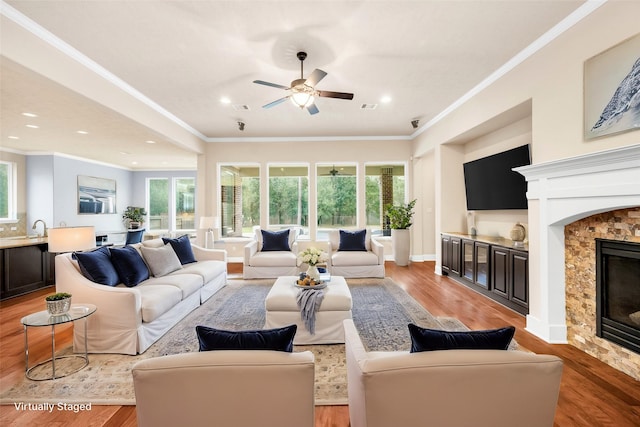 living room with a fireplace, ornamental molding, ceiling fan, and a healthy amount of sunlight