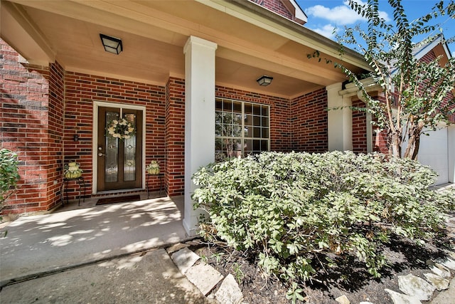 property entrance featuring covered porch and brick siding