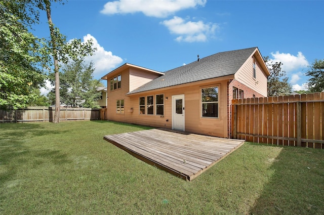 rear view of house with a fenced backyard, brick siding, a shingled roof, a lawn, and a wooden deck