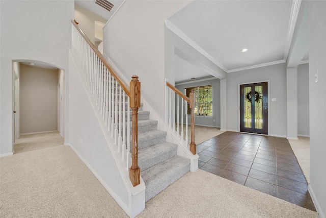 carpeted entryway with arched walkways, baseboards, visible vents, and crown molding