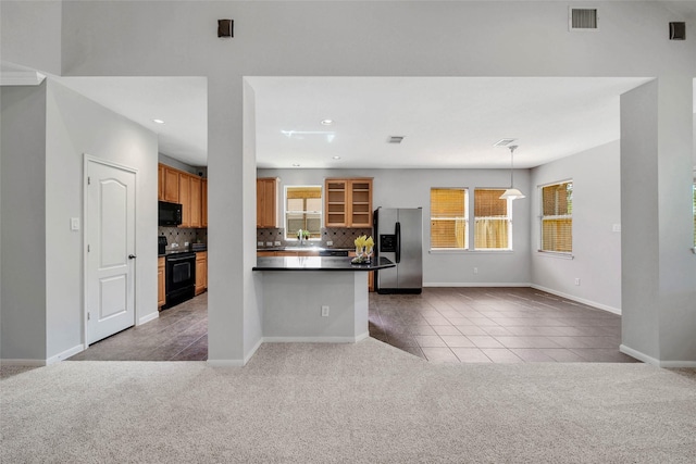 kitchen with light colored carpet, dark countertops, glass insert cabinets, decorative light fixtures, and black appliances