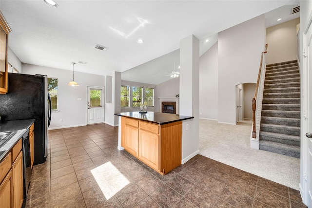 kitchen with visible vents, a ceiling fan, open floor plan, dark countertops, and a glass covered fireplace