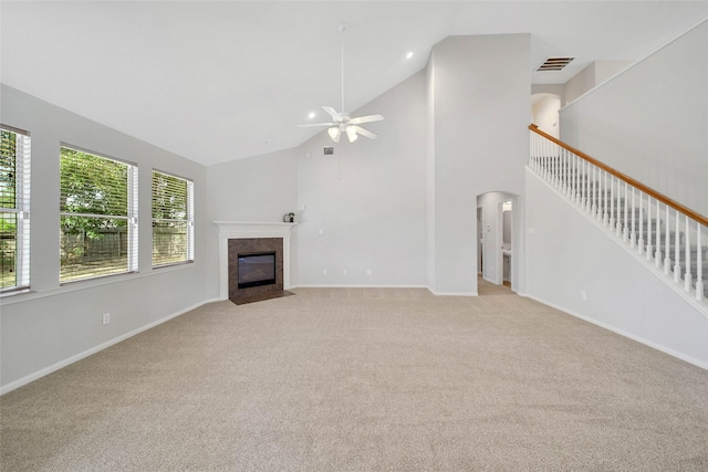 unfurnished living room featuring visible vents, arched walkways, light colored carpet, a tile fireplace, and high vaulted ceiling