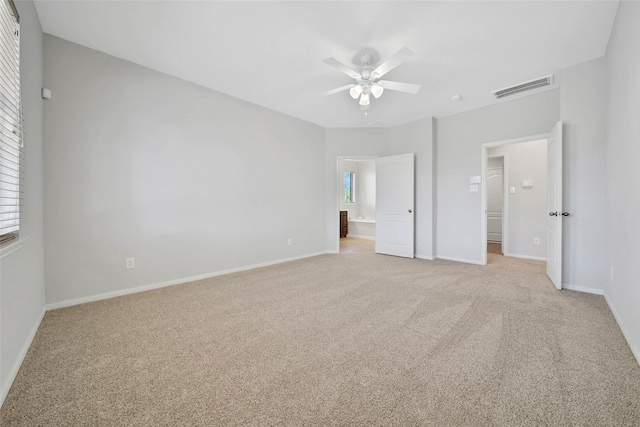 unfurnished bedroom featuring light carpet, baseboards, visible vents, a ceiling fan, and connected bathroom