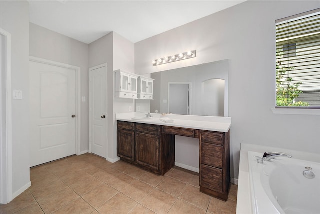 bathroom featuring a garden tub, vanity, baseboards, and tile patterned floors