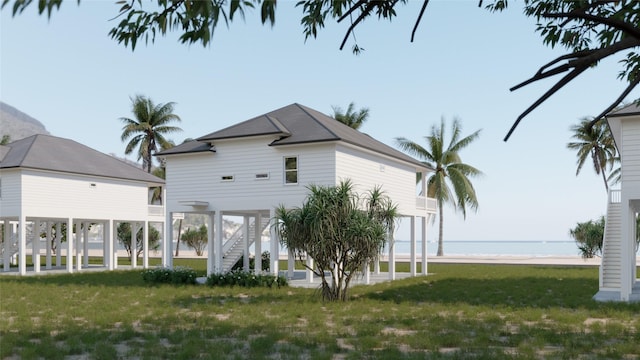 back of house with a water view and a lawn