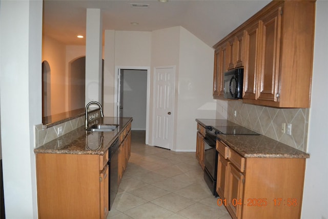 kitchen featuring sink, backsplash, dark stone countertops, light tile patterned flooring, and black appliances