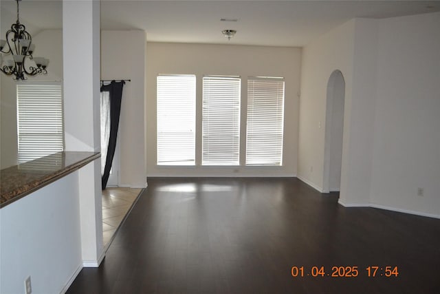 interior space with a healthy amount of sunlight, dark hardwood / wood-style flooring, and an inviting chandelier