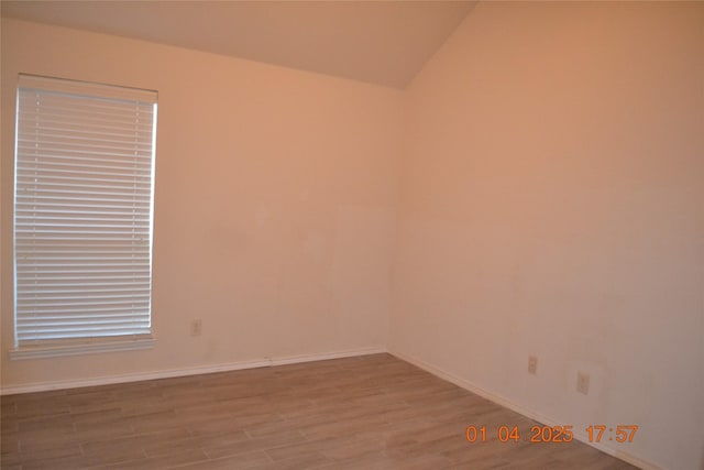 unfurnished room with light hardwood / wood-style floors and lofted ceiling