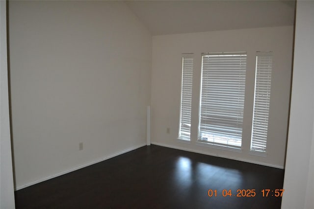 spare room with dark hardwood / wood-style floors and lofted ceiling