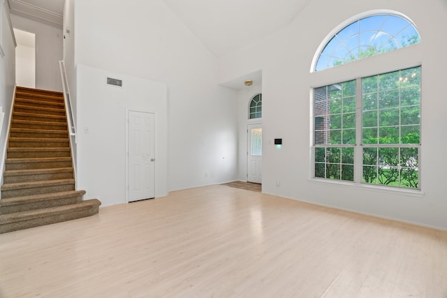 unfurnished living room featuring a wealth of natural light, light hardwood / wood-style floors, and high vaulted ceiling