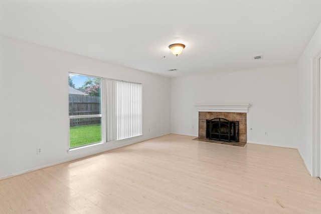 unfurnished living room featuring light hardwood / wood-style flooring and a tiled fireplace