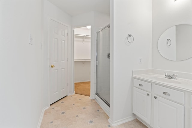 bathroom featuring a shower with door and vanity