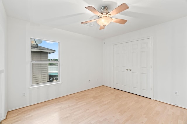 unfurnished bedroom featuring ceiling fan, a closet, and light wood-type flooring