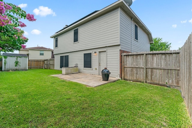 rear view of property with a yard, a patio, and a storage unit