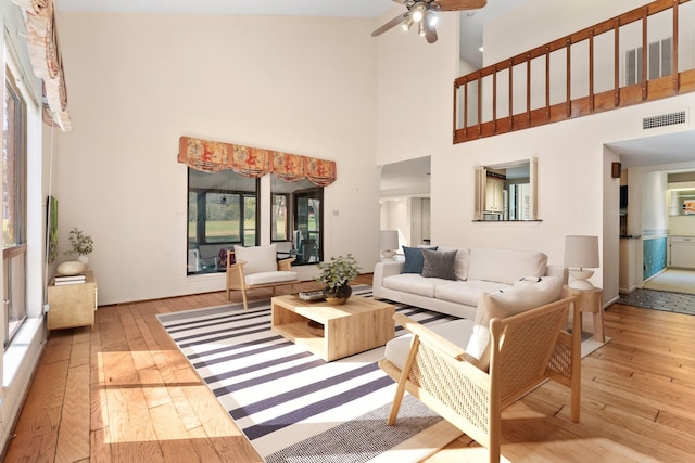 living room featuring ceiling fan, light hardwood / wood-style flooring, and a high ceiling