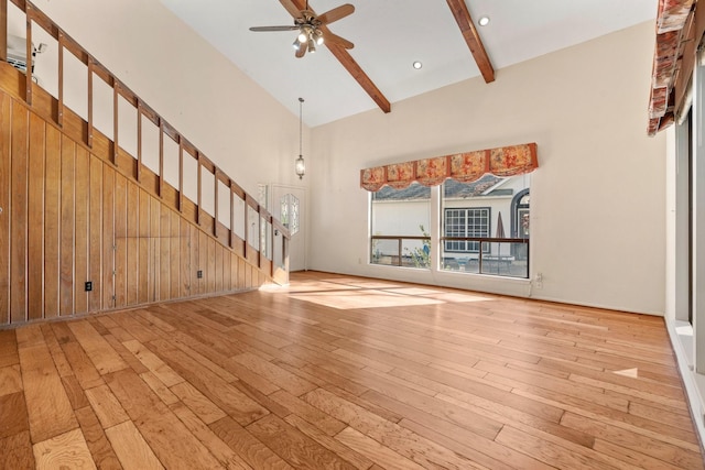 unfurnished living room with ceiling fan, beam ceiling, light hardwood / wood-style floors, and high vaulted ceiling