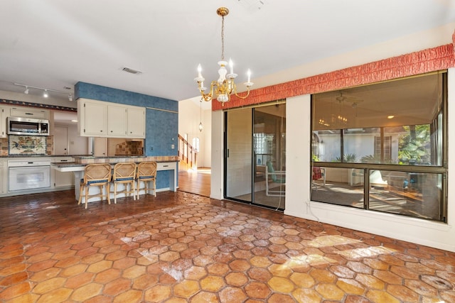 kitchen featuring decorative light fixtures, a notable chandelier, white cabinets, oven, and a breakfast bar area