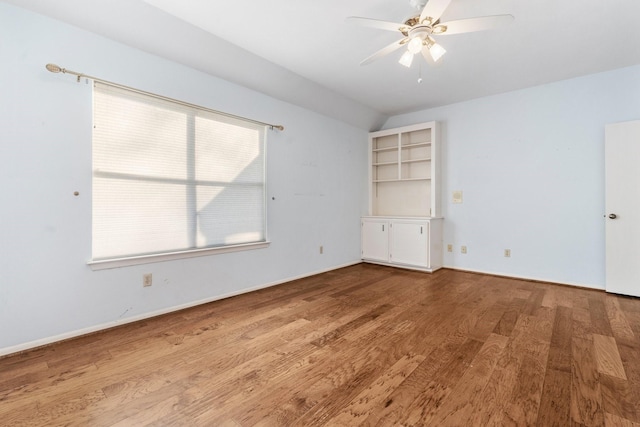 spare room featuring ceiling fan, wood-type flooring, a wealth of natural light, and vaulted ceiling