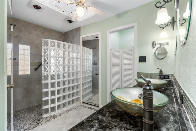 bathroom with tile patterned floors, vanity, ceiling fan, and a tile shower