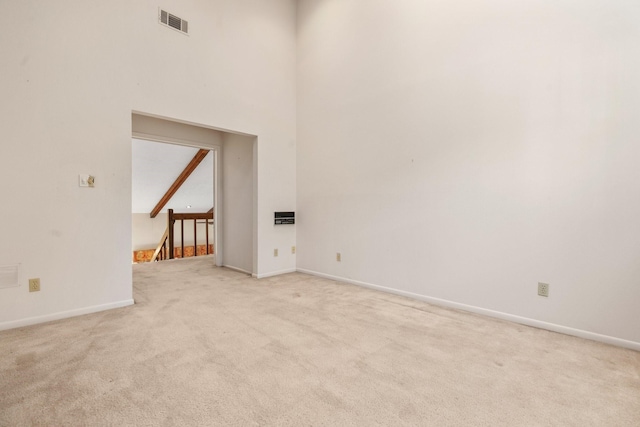 unfurnished living room featuring beam ceiling, light carpet, and high vaulted ceiling