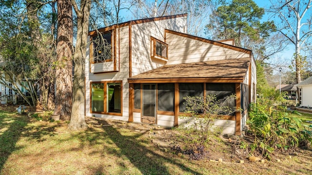 back of house featuring a sunroom and a lawn