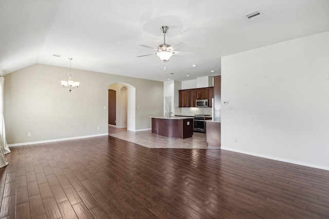 unfurnished living room with vaulted ceiling, ceiling fan with notable chandelier, and dark hardwood / wood-style floors