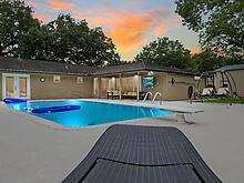 pool at dusk featuring a patio area and a hot tub