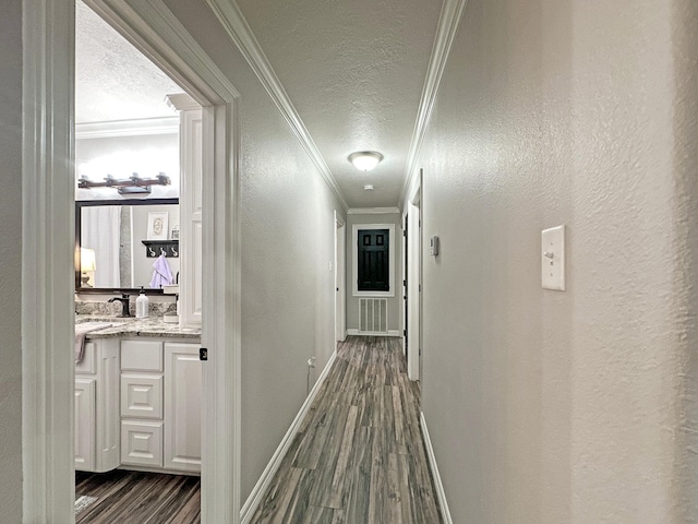 corridor with crown molding, dark hardwood / wood-style flooring, a textured ceiling, and sink