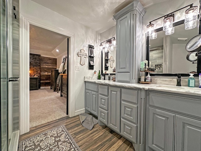 bathroom with hardwood / wood-style flooring, vanity, and lofted ceiling