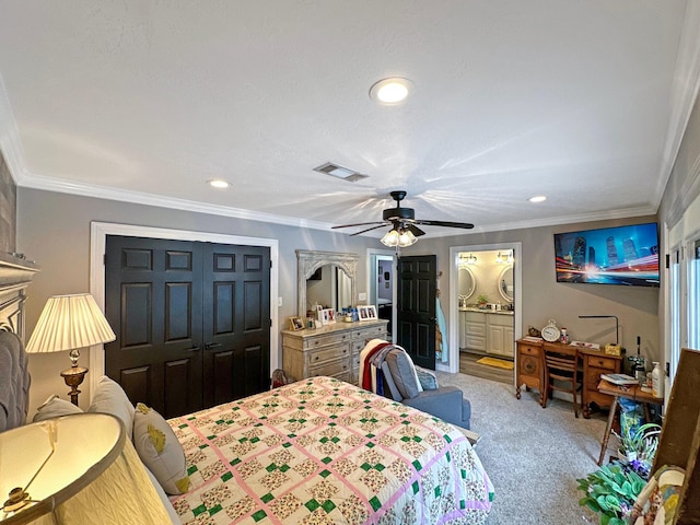 carpeted bedroom with a closet, ceiling fan, crown molding, and ensuite bath