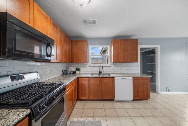 kitchen with light stone countertops, dishwasher, gas stove, and sink