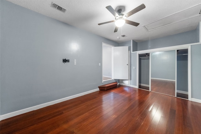 unfurnished bedroom with a closet, ceiling fan, a textured ceiling, and dark wood-type flooring