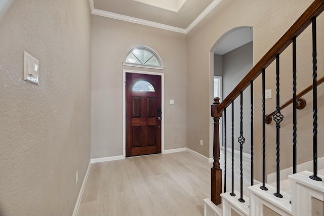 2206 Wolf Creek Ct, Katy, TX 77493 - foyer featuring light wood-style floors, arched walkways, ornamental molding, a textured wall, and stairway