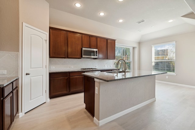 2206 Wolf Creek Ct, Katy, TX 77493 - kitchen featuring appliances with stainless steel finishes, a sink, dark stone countertops, light wood-style floors, and decorative backsplash