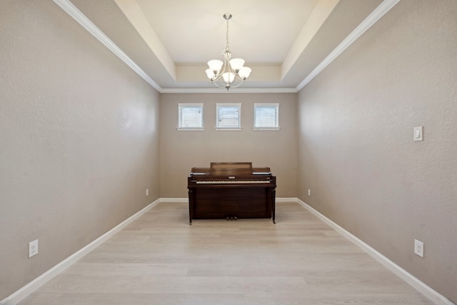 interior space with a raised ceiling, crown molding, light hardwood / wood-style flooring, and an inviting chandelier