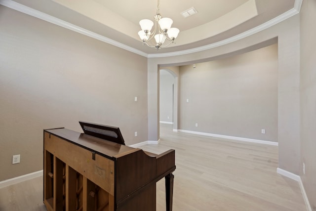 office space with a chandelier, a tray ceiling, crown molding, and light hardwood / wood-style floors