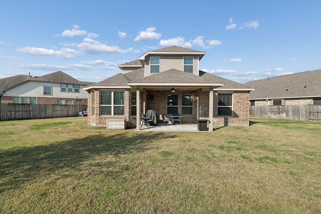 rear view of property featuring ceiling fan, a patio area, and a yard