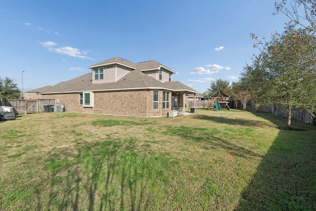 back of property with a playground, central AC, and a yard