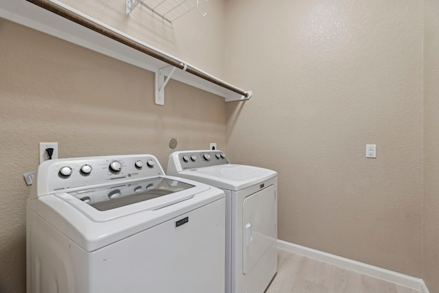 laundry room featuring washing machine and clothes dryer and light hardwood / wood-style flooring