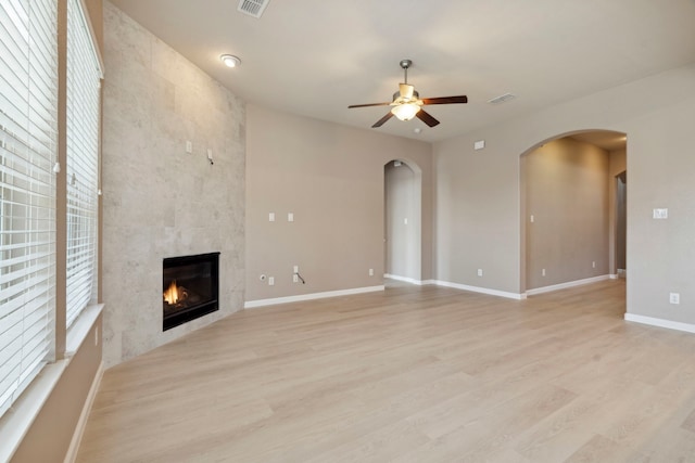 unfurnished living room with ceiling fan, light hardwood / wood-style floors, and a tiled fireplace