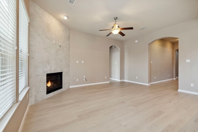2206 Wolf Creek Ct, Katy, TX 77493 - unfurnished living room with arched walkways, a ceiling fan, a fireplace, light wood finished floors, and baseboards