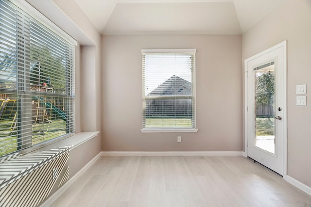 unfurnished room with light wood-type flooring and vaulted ceiling